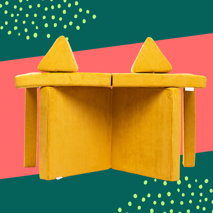 stackies Mustard Build – Symmetrical Modular Setup for Creative Play. Two mustard-yellow stackies foam cushions arranged vertically with triangular pieces on top, forming a symmetrical modular play couch build that looks like a castle. Designed to spark imaginative play.