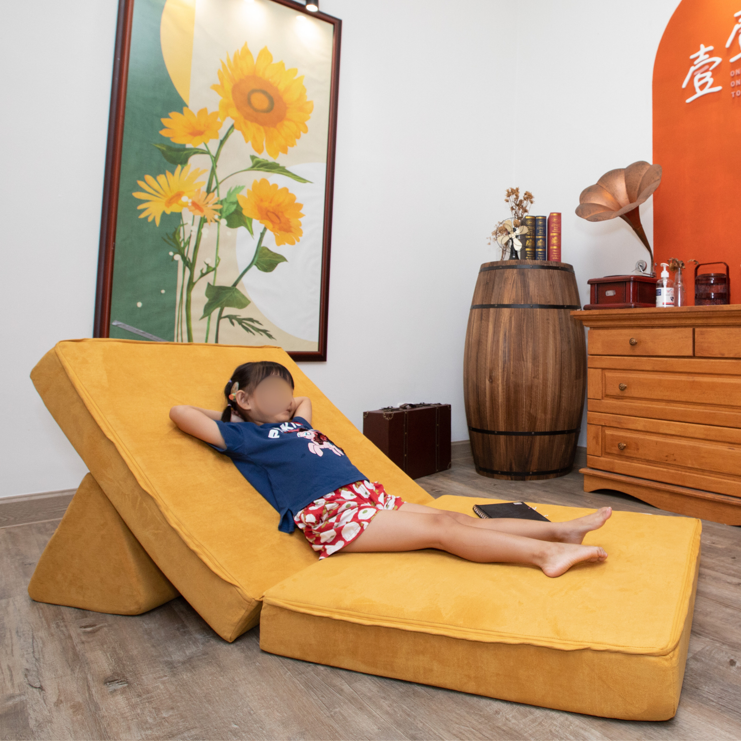stackies Mustard Lounge | Modular Kids Recliner for Cozy Play. Child reclining on stackies mustard-yellow modular play couch in a cozy room with sunflower art and vintage decor. A kids lounge setup designed for comfort, creativity, and everyday play.